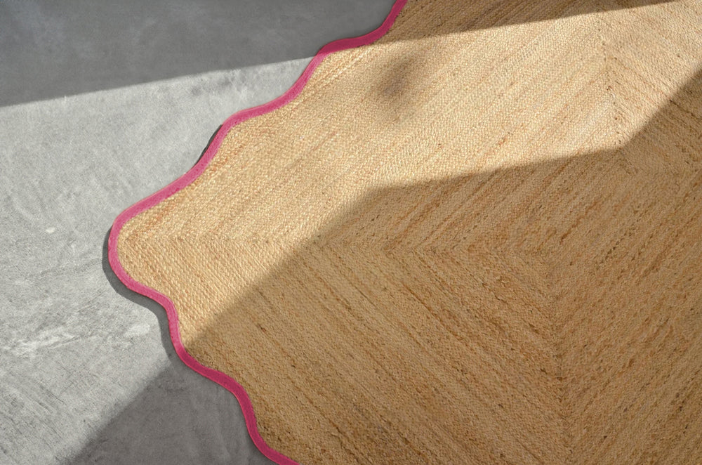 Handwoven natural jute scalloped area rug with elegant pink border for modern boho living room decor.