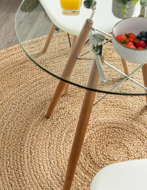 Round handwoven natural jute rug with braided spiral weave design in earthy brown and tan tones for boho rustic home décor.