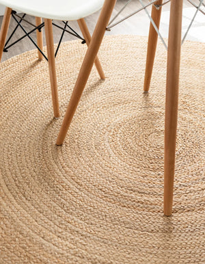 Round handwoven natural jute rug with braided spiral weave design in earthy brown and tan tones for boho rustic home décor.