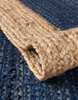 A modern circular patterned round rug placed on a wooden floor in a styled living room setu