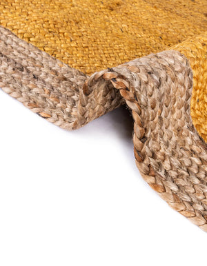 Handwoven oval jute area rug in mustard yellow with a natural beige braided border