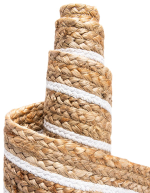 Natural jute area rug with white geometric border and braided texture styled in a warm farmhouse entryway with wooden flooring
