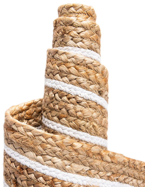 Natural jute area rug with white geometric border and braided texture styled in a warm farmhouse entryway with wooden flooring