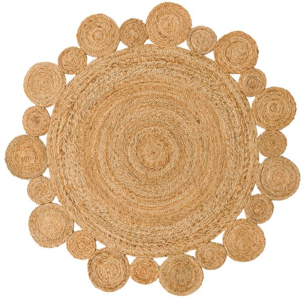 Handwoven round natural jute rug with a circular scalloped border on light wood floors next to a cream armchair