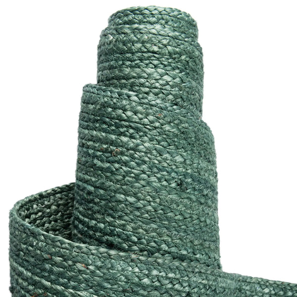 Deep green handwoven braided jute runner rug placed on a hardwood floor alongside a wooden bench in an entryway.