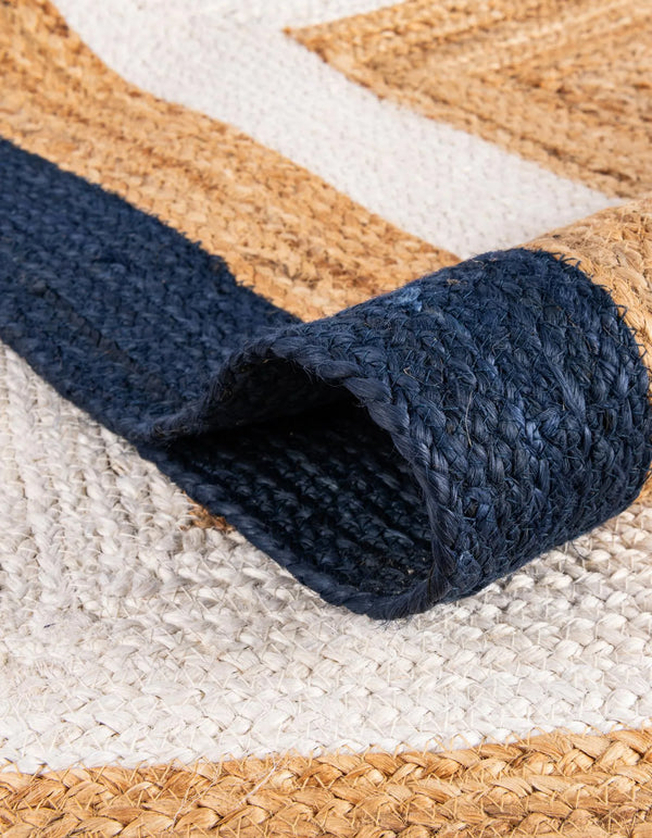 Handwoven natural jute area rug with ivory and navy blue borders styled in a bright coastal living room with a cream sofa and wooden furniture