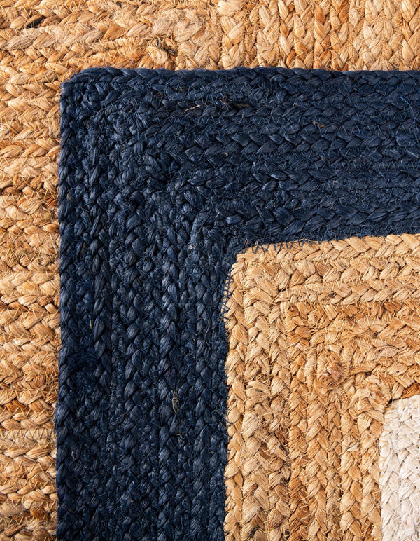 Natural jute runner rug with ivory and navy blue borders styled in a bright modern hallway with wooden flooring and neutral furniture