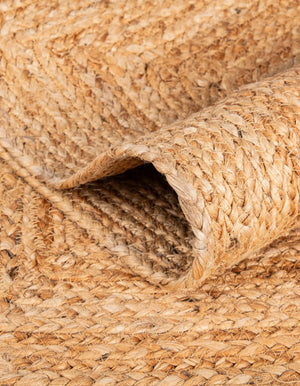 Handwoven natural jute runner rug with colorful pom-pom accents laid in a bright white hallway on light oak flooring