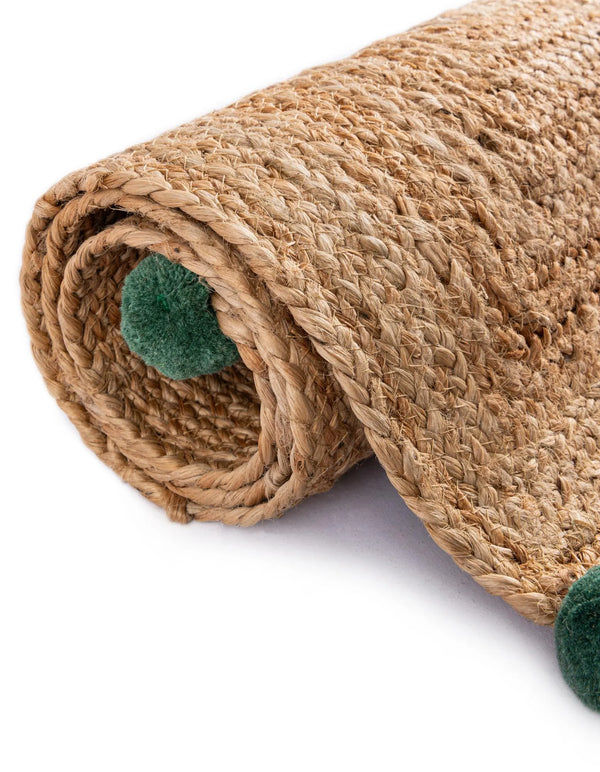 Handwoven natural jute runner rug with colorful pom-pom accents laid in a bright white hallway on light oak flooring