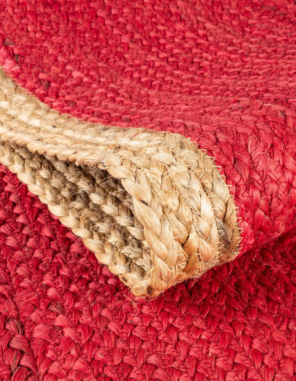 Red handwoven textured jute area rug with natural border styled on a wooden floor in a cozy rustic entryway