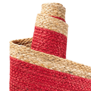 Red handwoven textured jute area rug with natural border styled on a wooden floor in a cozy rustic entryway