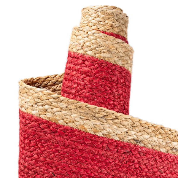 Red handwoven textured jute area rug with natural border styled on a wooden floor in a cozy rustic entryway
