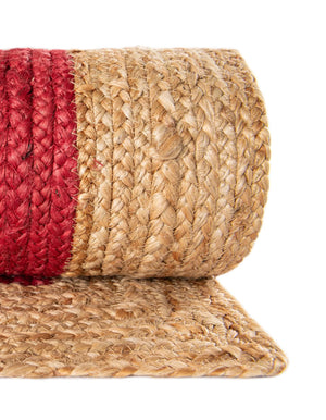 Red handwoven textured jute area rug with natural border styled on a wooden floor in a cozy rustic entryway