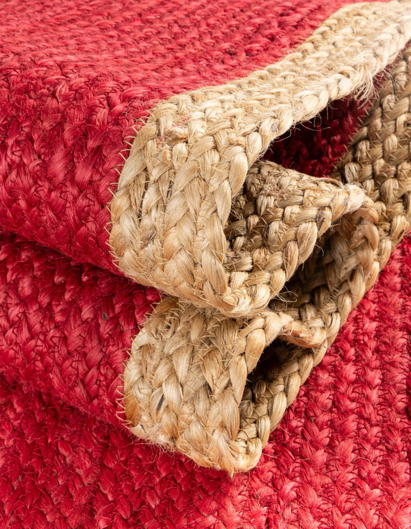 Red handwoven textured jute area rug with natural border styled on a wooden floor in a cozy rustic entryway