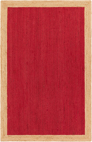 A rectangular handwoven natural jute rug featuring a bold crimson red woven center framed by a thick, natural beige braided border, laid on a hardwood floor under a rustic coffee table and sofa.