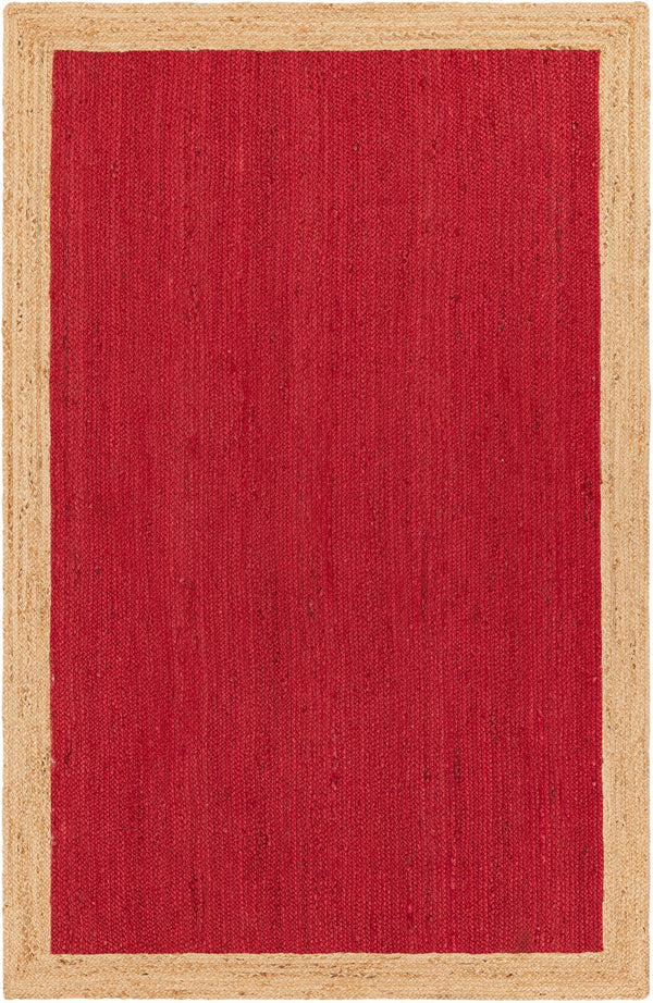A rectangular handwoven natural jute rug featuring a bold crimson red woven center framed by a thick, natural beige braided border, laid on a hardwood floor under a rustic coffee table and sofa.