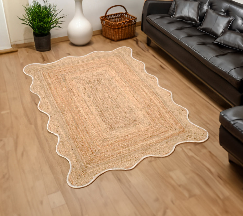 Handwoven natural jute scalloped area rug with white border placed in a modern living room featuring eco-friendly braided craftsmanship.