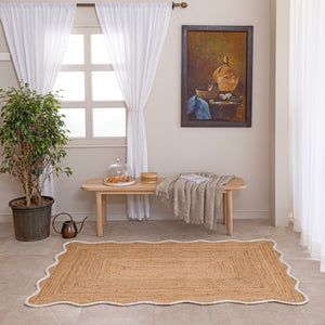 Handmade natural jute area rug with scalloped border in a neutral modern living room
