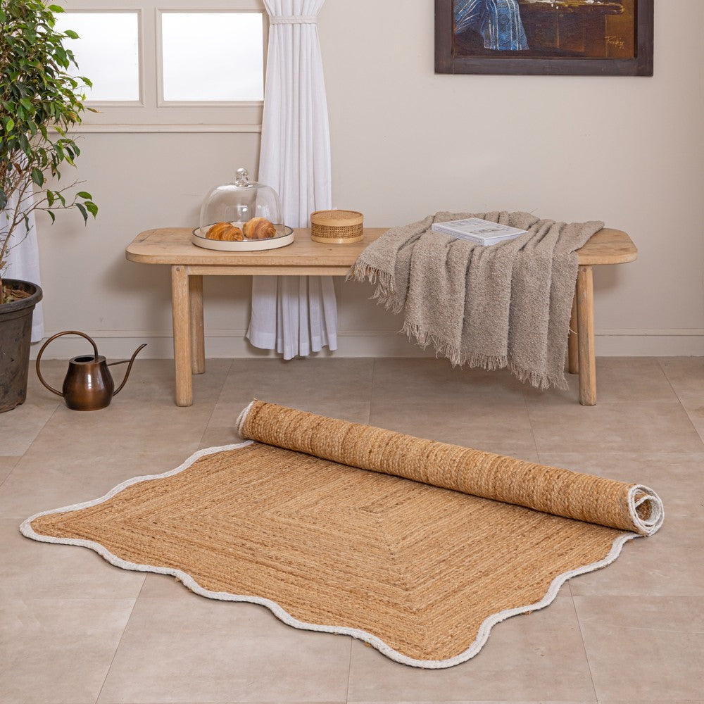 Handmade natural jute area rug with scalloped border in a neutral modern living room