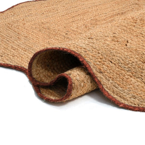 Handwoven natural jute scalloped area rug with terracotta border placed in a modern living room featuring eco-friendly artisan craftsmanship.
