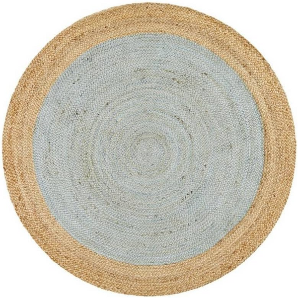 A high-angle view of a modern living room featuring a round braided jute area rug with a pastel light blue center and a natural tan border, styled on light hardwood floors with a cream sofa and a wooden armchair.
