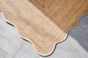 Handwoven natural jute scalloped area rug with white border placed in a modern living room featuring eco-friendly braided craftsmanship.
