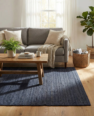 Navy blue handwoven textured area rug styled in a cozy modern living room with cream sofa and wooden furniture