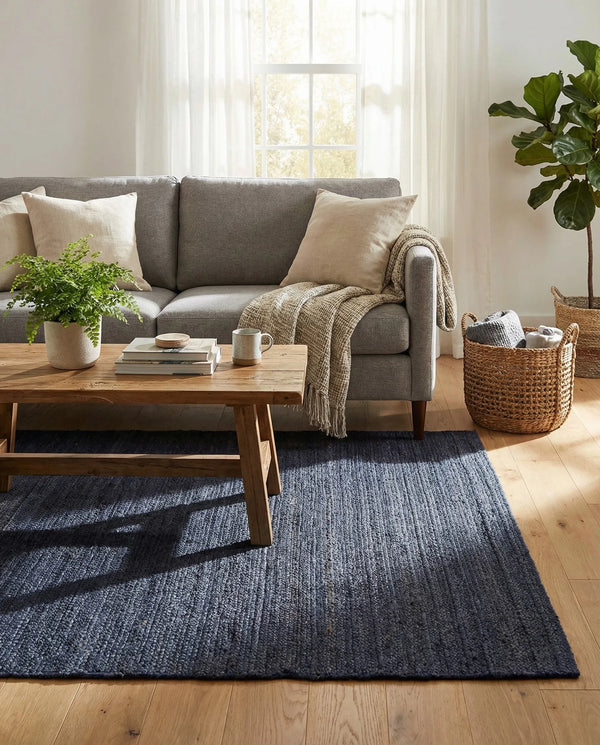 Navy blue handwoven textured area rug styled in a cozy modern living room with cream sofa and wooden furniture