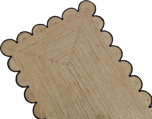 Handmade natural braided jute rug with black scalloped border displayed in a modern boho living room, eco-friendly woven area rug for living room, bedroom, farmhouse and minimalist home decor.