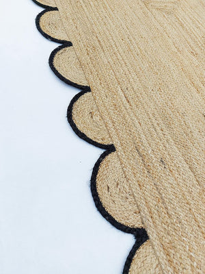 Handmade natural braided jute rug with black scalloped border displayed in a modern boho living room, eco-friendly woven area rug for living room, bedroom, farmhouse and minimalist home decor.