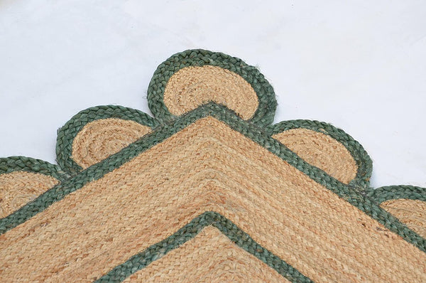 Handwoven natural jute scalloped area rug with sage green border styled in a modern Scandinavian living room.