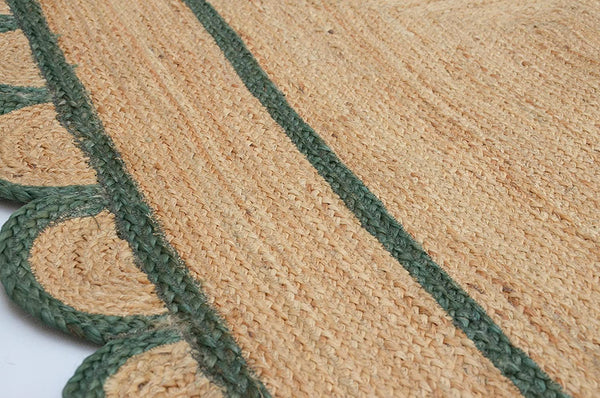 Handwoven natural jute scalloped area rug with sage green border styled in a modern Scandinavian living room.
