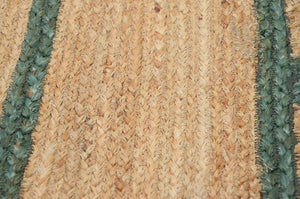 Handwoven natural jute scalloped area rug with sage green border styled in a modern Scandinavian living room.