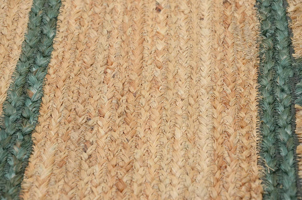Handwoven natural jute scalloped area rug with sage green border styled in a modern Scandinavian living room.