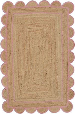 Handwoven natural jute area rug with a soft pink scalloped border styled in a modern Scandinavian living room featuring neutral furniture and natural wood flooring.