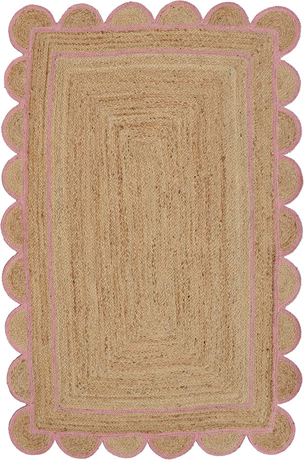 Handwoven natural jute area rug with a soft pink scalloped border styled in a modern Scandinavian living room featuring neutral furniture and natural wood flooring.