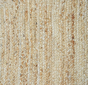 Handwoven natural jute area rug with a soft pink scalloped border styled in a modern Scandinavian living room featuring neutral furniture and natural wood flooring.