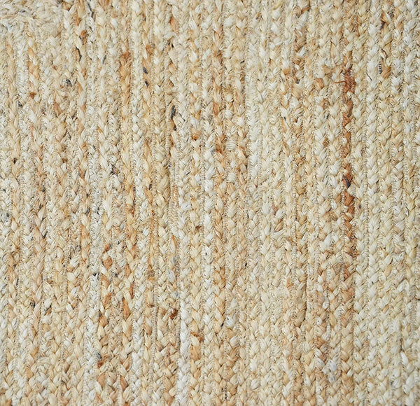 Handwoven natural jute area rug with a soft pink scalloped border styled in a modern Scandinavian living room featuring neutral furniture and natural wood flooring.