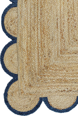 Handwoven natural jute area rug with navy blue scalloped border styled in a modern Scandinavian living room.