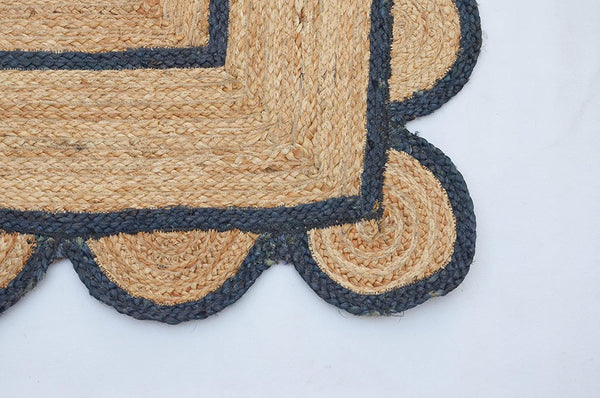 Handwoven natural jute area rug with navy blue scalloped border, eco-friendly braided rectangular rug for modern boho farmhouse living room decor.