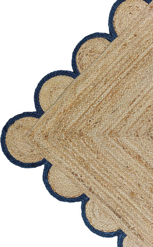Handwoven natural jute area rug with navy blue scalloped border styled in a modern Scandinavian living room.