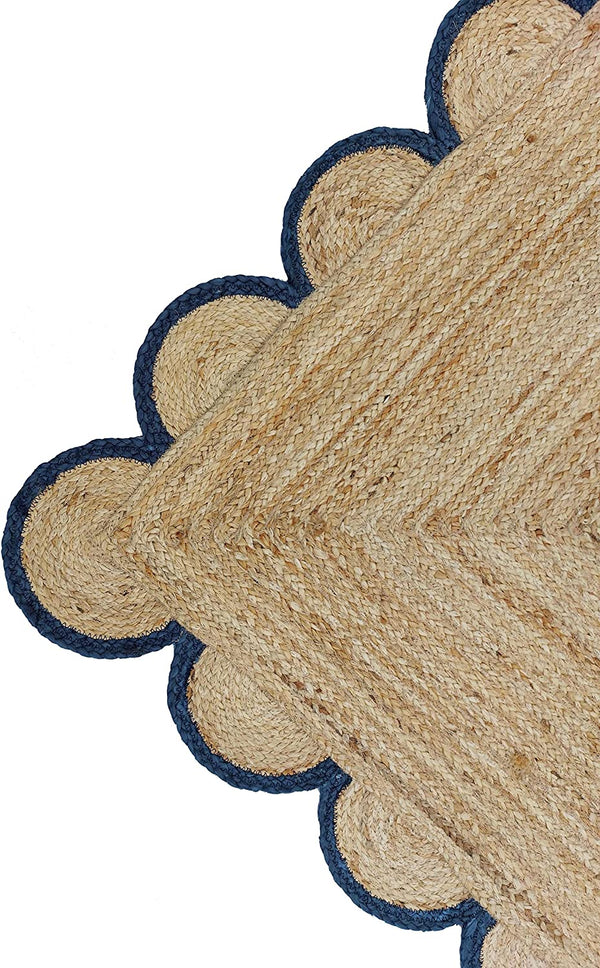 Handwoven natural jute area rug with navy blue scalloped border styled in a modern Scandinavian living room.