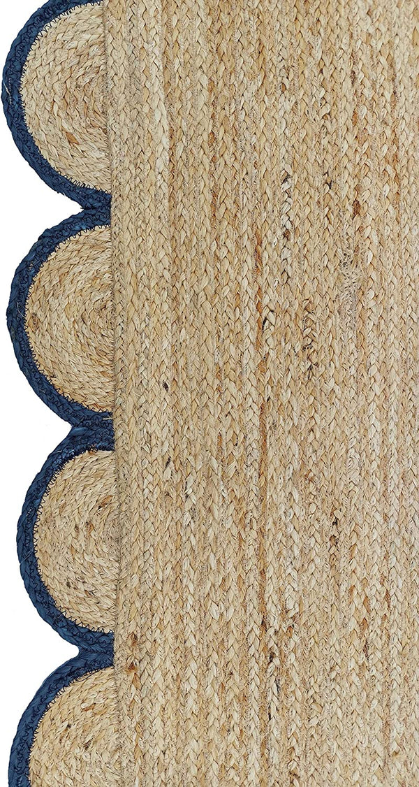Handwoven natural jute area rug with navy blue scalloped border styled in a modern Scandinavian living room.