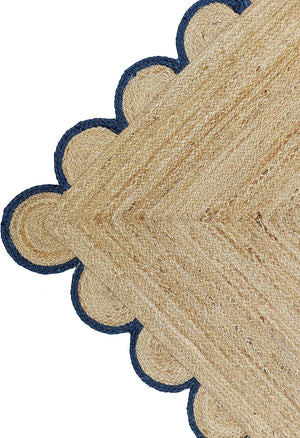 Handwoven natural jute area rug with navy blue scalloped border styled in a modern Scandinavian living room.