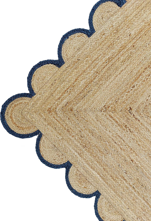 Handwoven natural jute area rug with navy blue scalloped border styled in a modern Scandinavian living room.