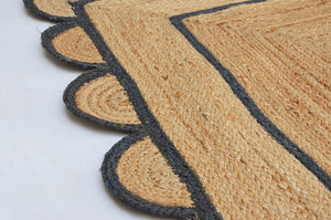 Handwoven natural jute area rug with navy blue scalloped border, eco-friendly braided rectangular rug for modern boho farmhouse living room decor.
