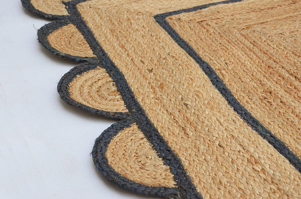 Handwoven natural jute area rug with navy blue scalloped border, eco-friendly braided rectangular rug for modern boho farmhouse living room decor.
