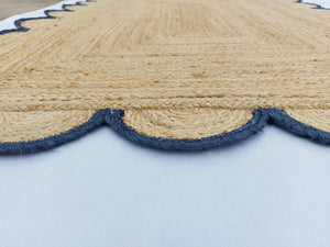 Handwoven natural jute area rug with navy blue scalloped border styled in a modern Scandinavian living room.