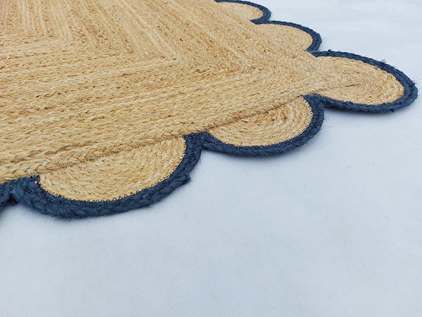 Handwoven natural jute area rug with navy blue scalloped border styled in a modern Scandinavian living room.