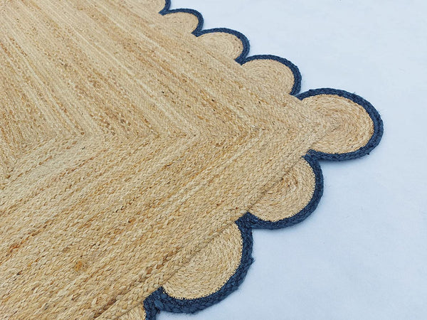 Handwoven natural jute area rug with navy blue scalloped border styled in a modern Scandinavian living room.